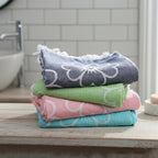 Stack of colorful patterned towels on a bathroom counter. VU-BLO-PNK VU-BLO-IND VU-BLO-BLU VU-BLO-GRE