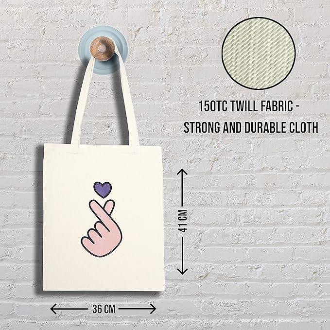 Tote bag with a design on a hook against a textured wall, showing fabric details and dimensions.