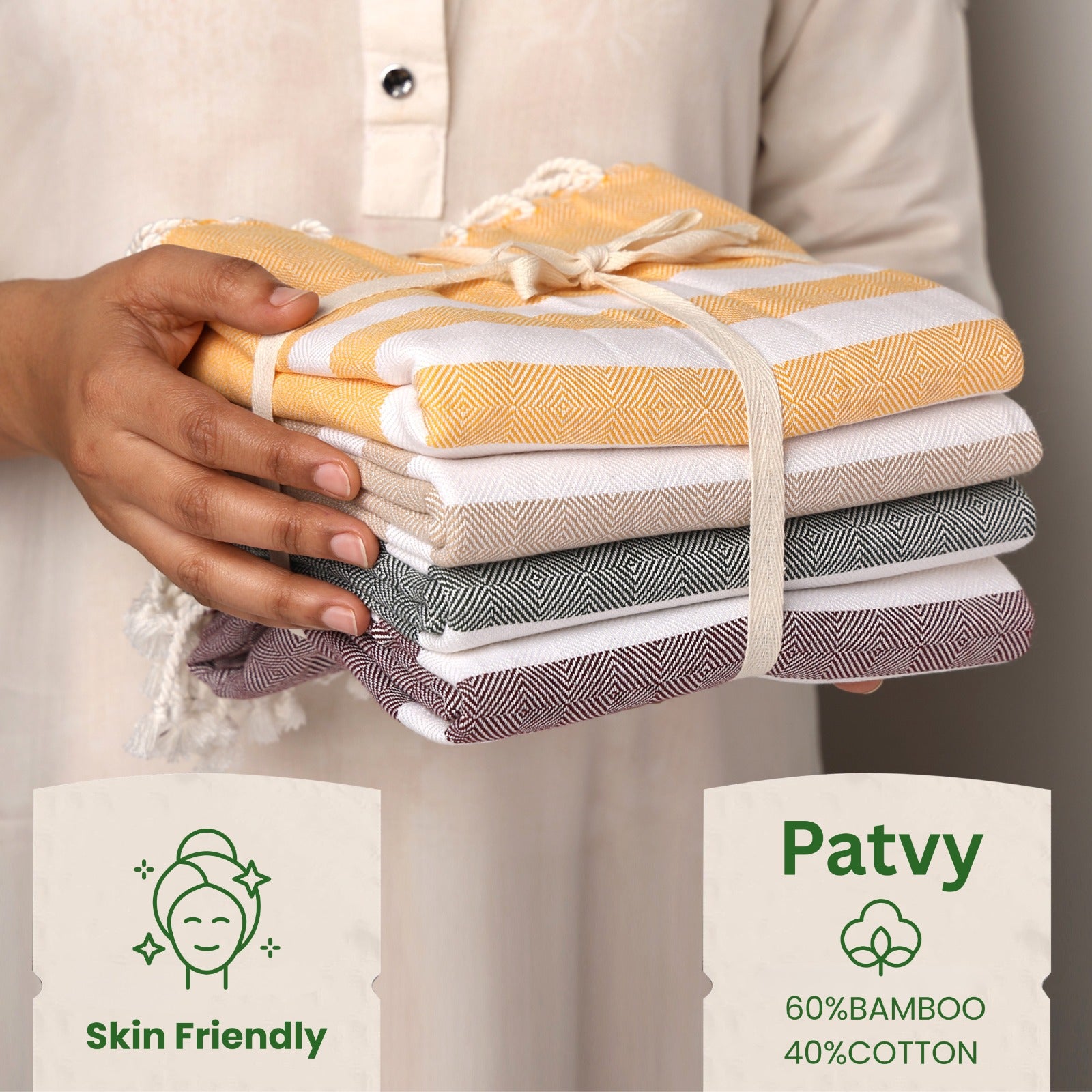 Stack of folded towels held by a person with 'Patvy' branding and product details.(PT-BMB-MST PT-BMB-BRG PT-BMB-TPE PT-BMB-EMR)